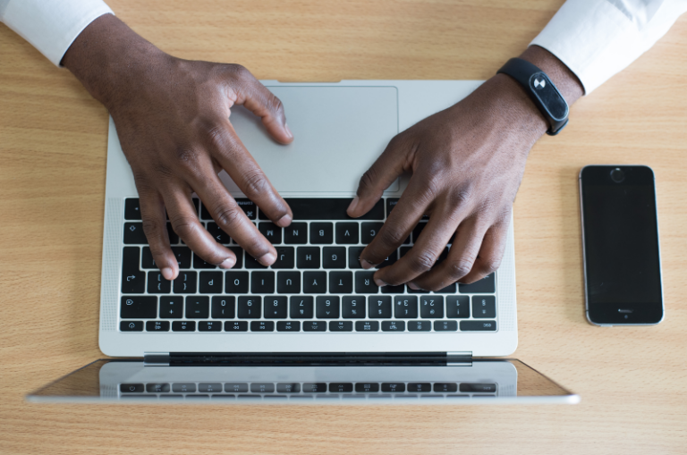 Man typing on a laptop keyboard.