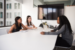 3 women sitting across from each other at a conference table