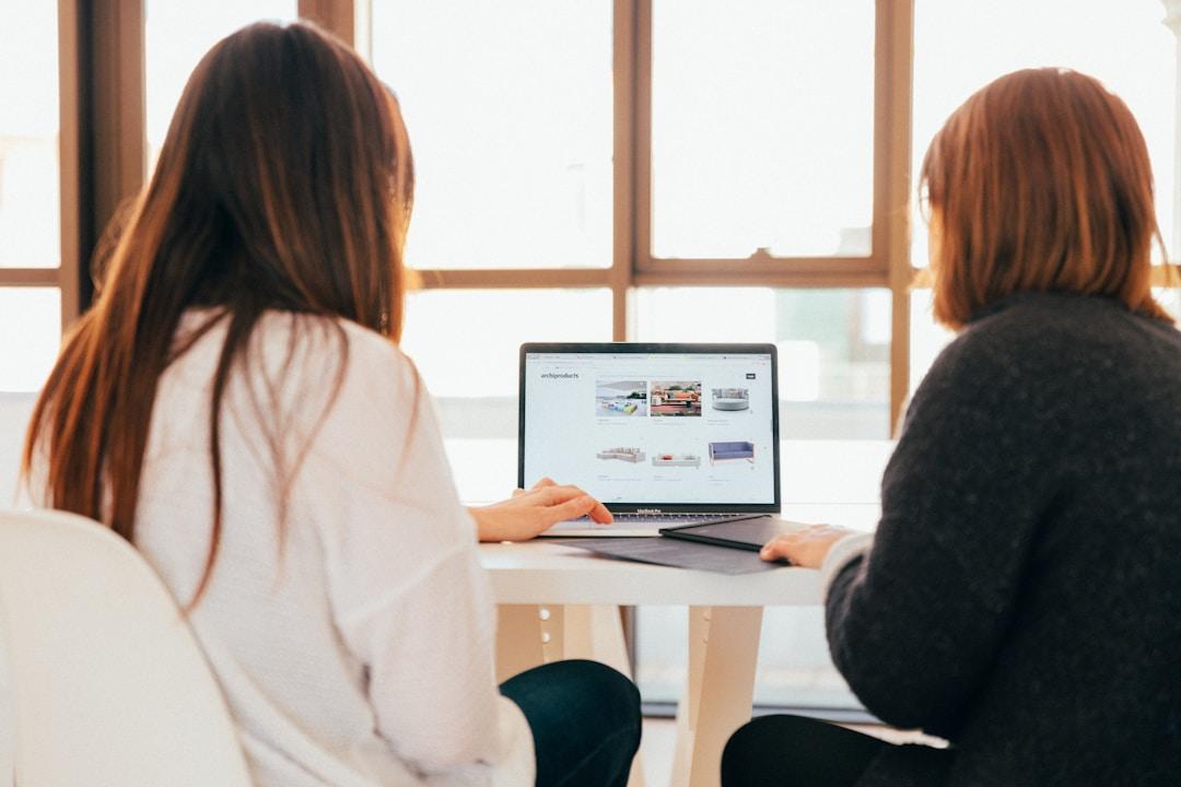 Two women engaged in discussion at a table, utilizing a laptop to explore an AI enterprise platform.